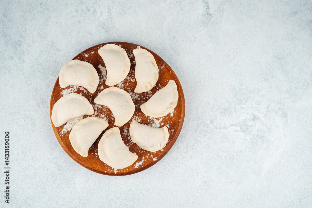 Delicious handmade dumplings arranged on wooden plate in kitchen