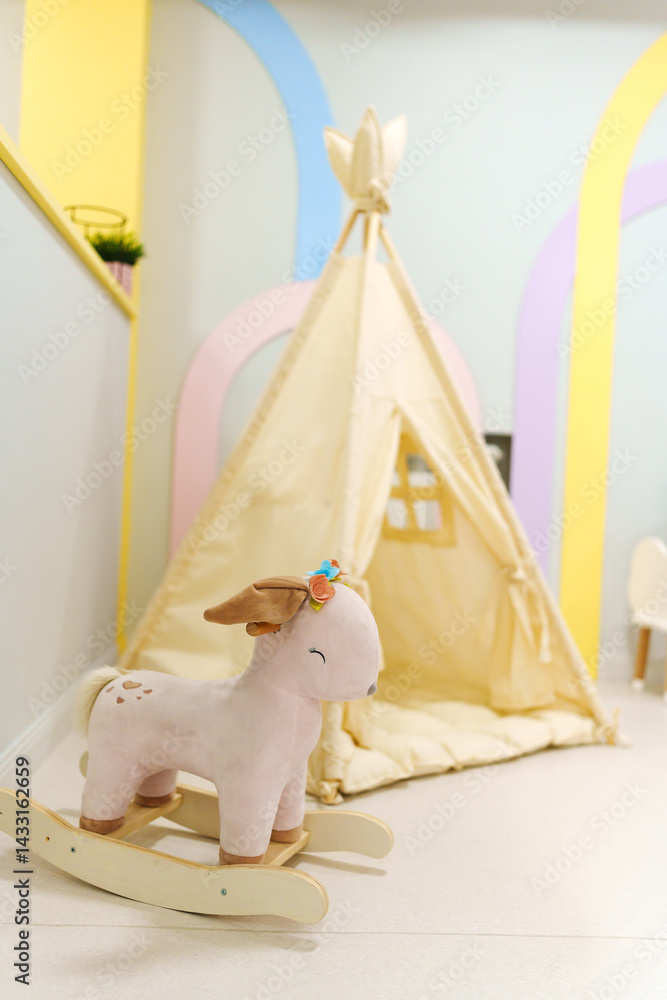 Wigwam tent for children's room with rocking toy.