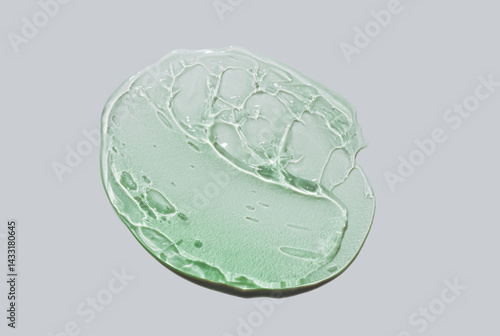 Cosmetic green aloe vera or centella asiatica shaped gel texture swatch isolated on grey background