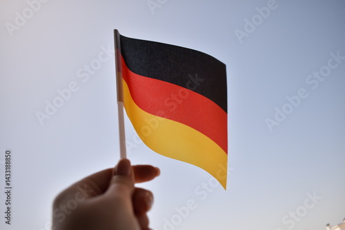 German national flag flying against blue sky – symbol of patriotism, unity, and the cultural and historical identity of Germany. Ideal for national holidays or international themes.
