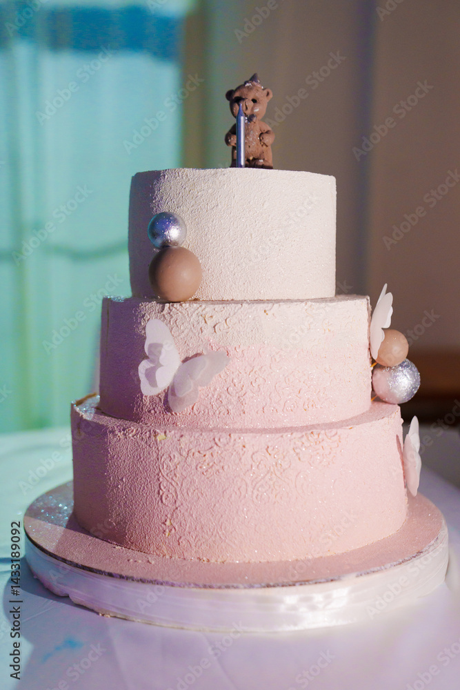 a three-tiered cake decorated with bear cub, caramel balls and butterflies.