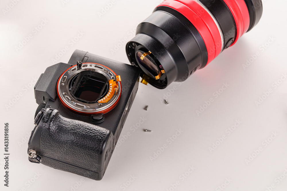 A broken lens, professional camera and repair tools on a white table.