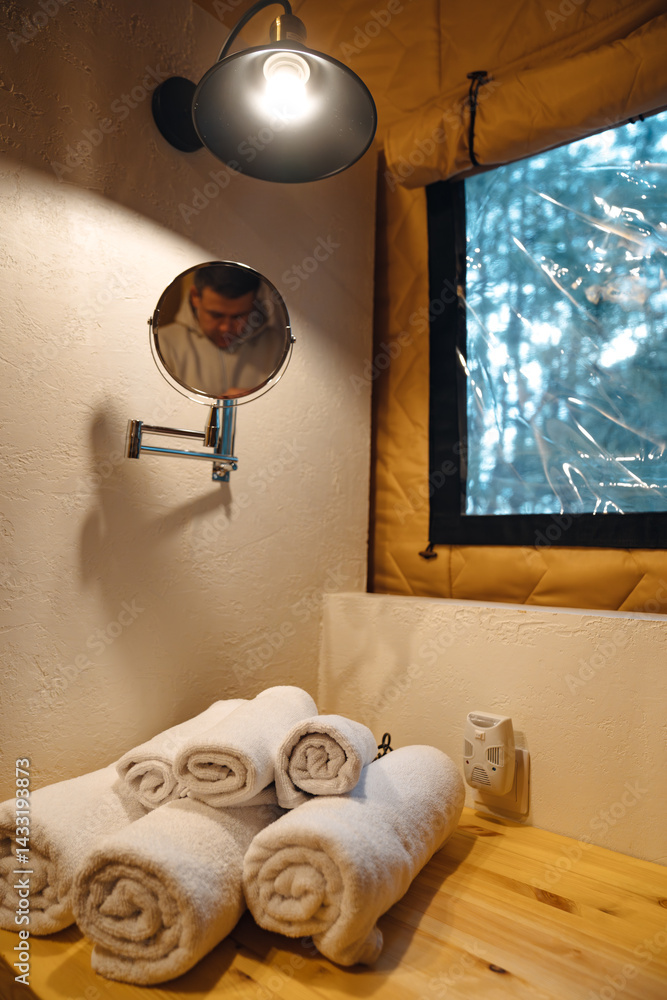 Lamp and round mirror in the bathroom in the tent house in the glamping.
