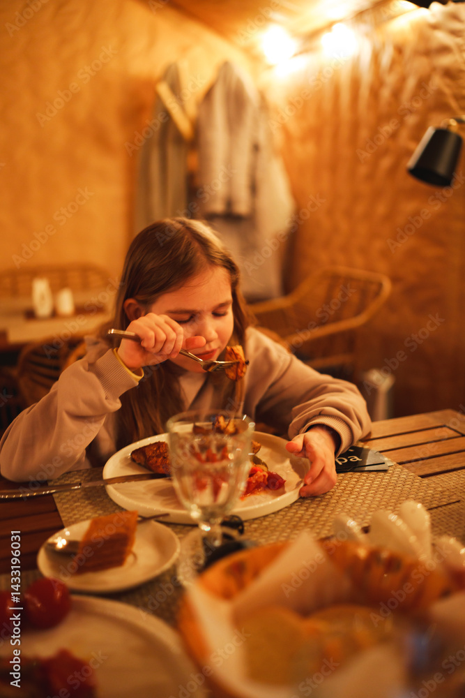 Selective focus. Teenage girl eating in the semi-darkness in a cafe.