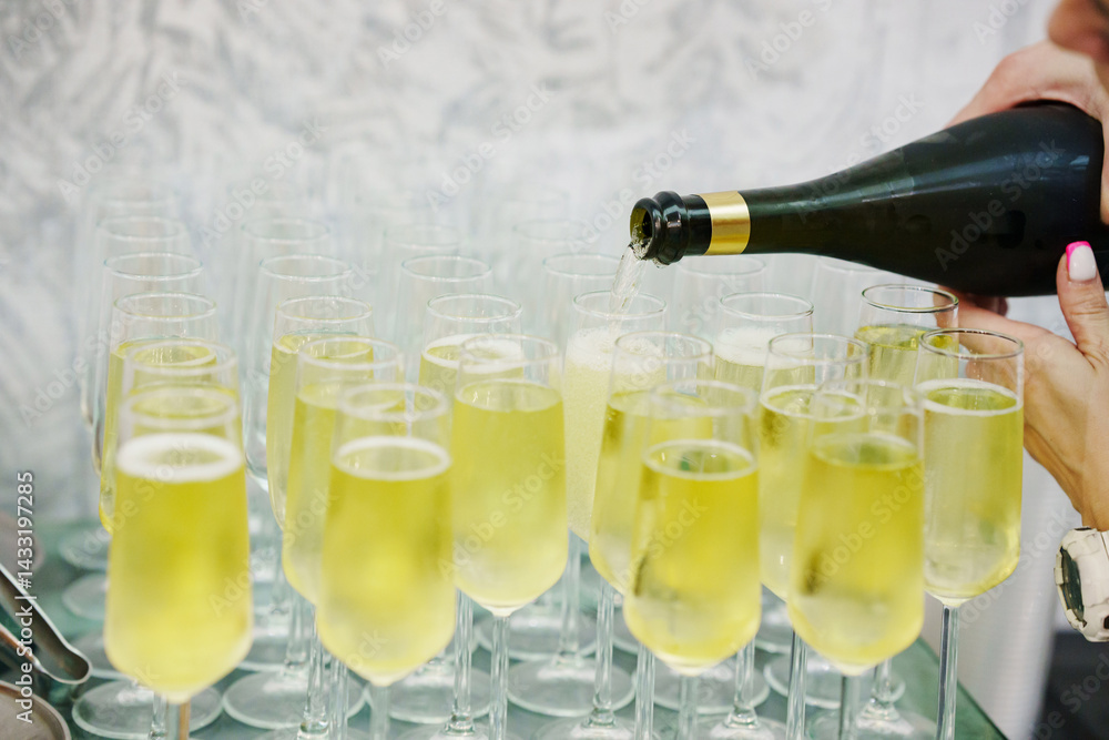 Champagne from the bottle is poured into glasses.