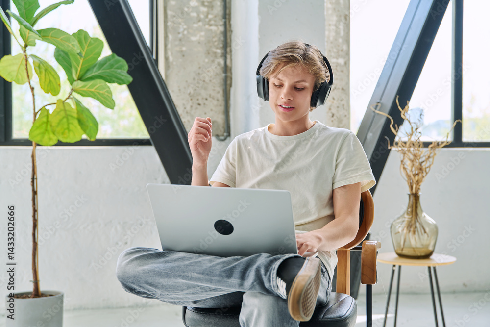 Teenage boy with headphones using laptop for video conference, online meeting