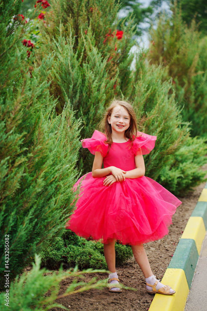 A girl in a lush pink dress near the green bushes