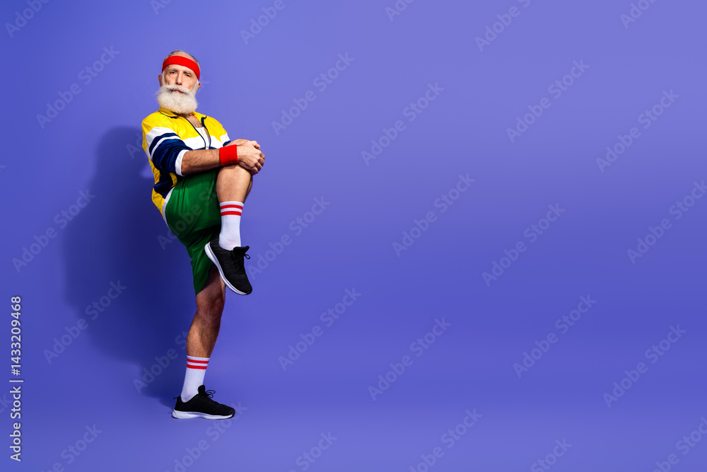 Obraz premium Elderly man in retro athletic wear striking a pose on a colored background embodying an active and stylish lifestyle