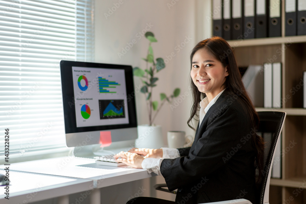 A woman is sitting at a desk with a computer monitor in front of her A woman is sitting at a desk with a computer monitor in front of her