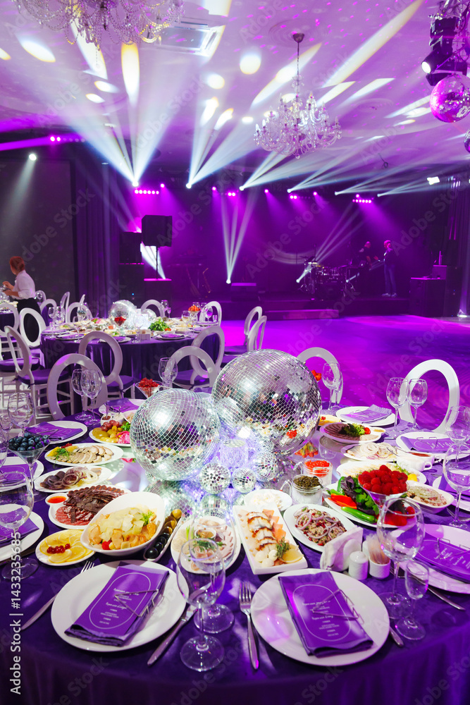 A table set for the holiday in purple in a dark banquet hall.