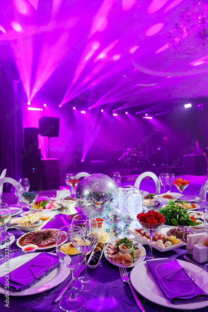 A table set for the holiday in purple in a dark banquet hall.
