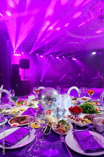 A table set for the holiday in purple in a dark banquet hall. 