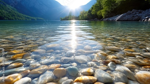 Sunlight reflecting on crystal clear water with colorful pebbles at the bottom of a serene mountain lake.