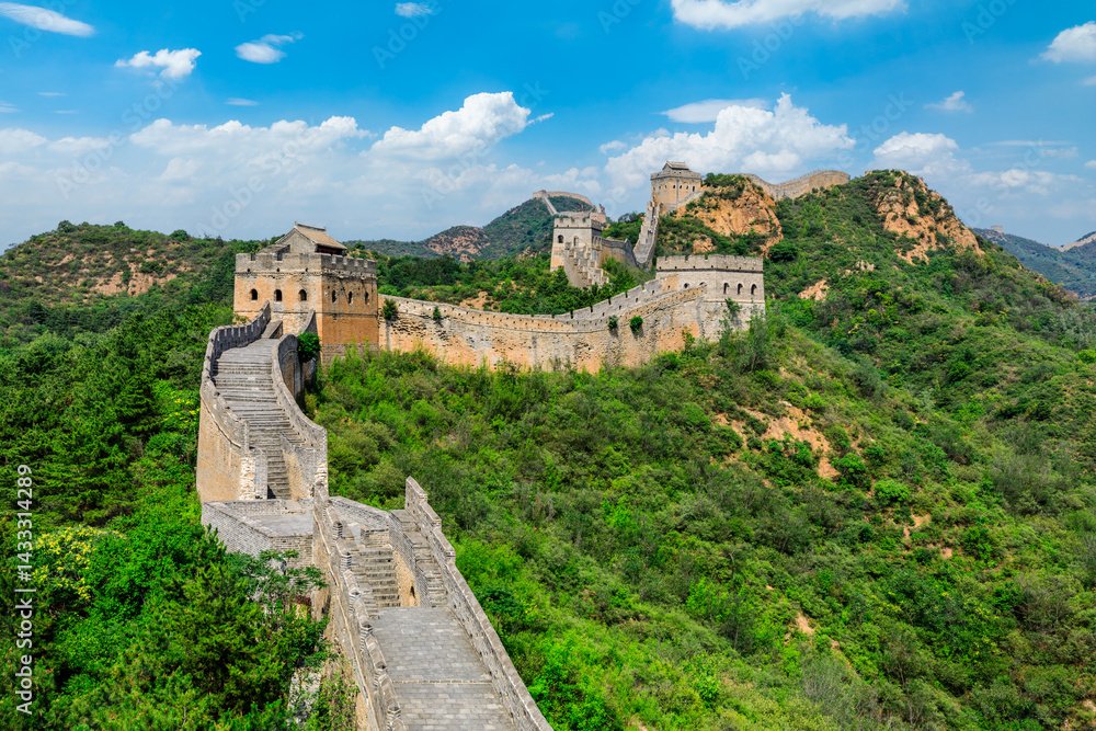 The great wall of china winds through lush green mountains under blue sky