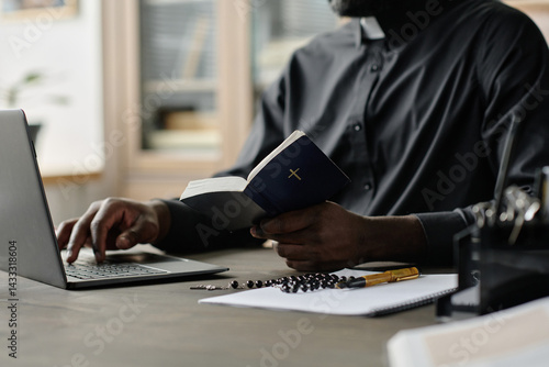 Canvastavla Medium close up of unrecognizable pastor in black cassock sitting at wooden desk