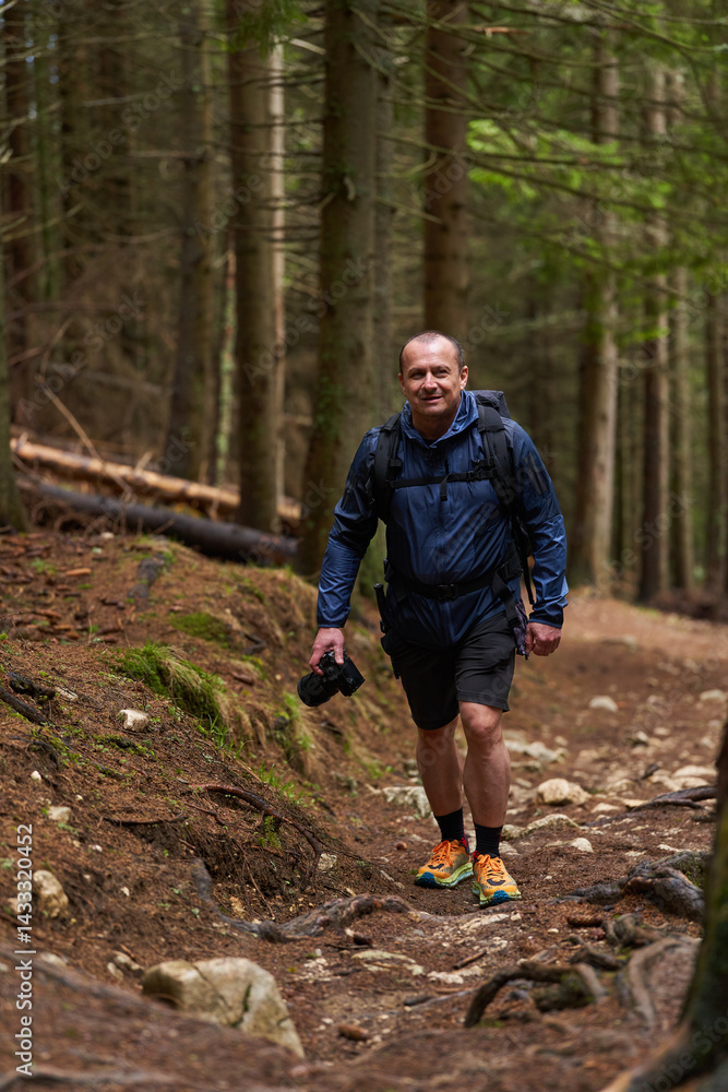 Photographer hiking uphill through forest trail