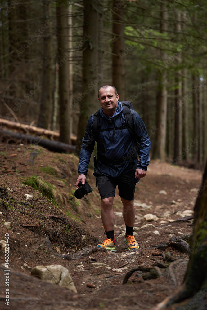 Photographer hiking uphill through forest trail