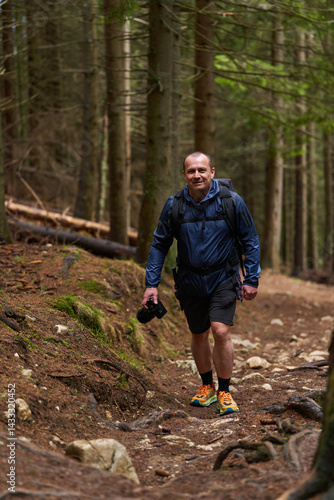Obraz na płótnie Photographer hiking uphill through forest trail w salonie