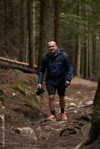 Obraz na płótnie Photographer hiking uphill through forest trail w salonie