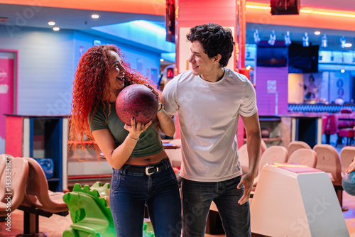 Young couple having fun playing bowling together in a bowling alley, enjoying their leisure activity