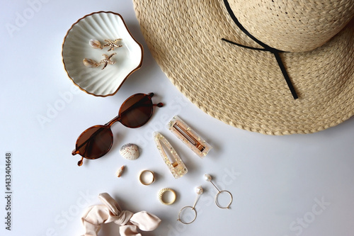 Sunglasses, straw hat, shells and jewelry in neutral colors. Seasonal summer accessories on white background. Flat lay.