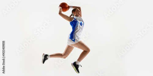 Tableau sur toile Fit and confident young girl, playing basketball, Basketball player raising hands with ball, performing slam dunk against white background