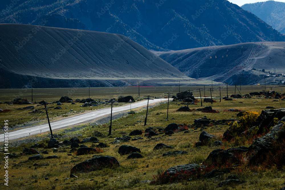 A road cutting through the rugged and dramatic landscape of the Altai Mountains in the Altai Republic, surrounded by raw nature and vast open spaces.