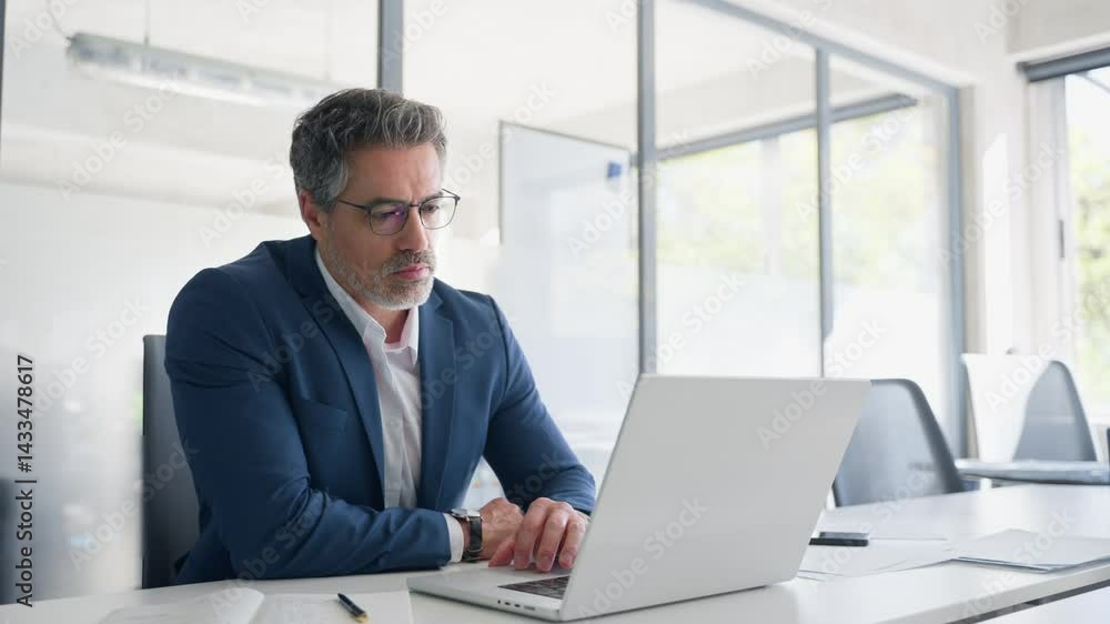 Focused senior businessman entrepreneur sitting at desk working on financial project, looking thinking at screen. Mature 50s Latin business man ceo manager using laptop computer in office. Copy space