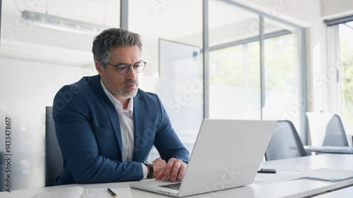 Focused senior businessman entrepreneur sitting at desk working on financial project, looking thinking at screen. Mature 50s Latin business man ceo manager using laptop computer in office. Copy space