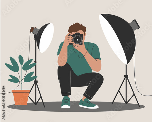Male photographer squatting and using professional camera equipment with studio lighting and potted plant