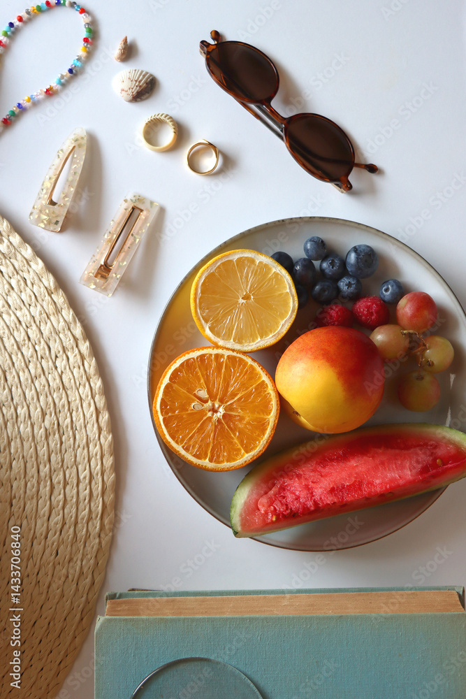 Glass of cocktail, straw hat, sunglasses, books, fresh fruit, chocolate and accessories. Summer essentials on the table. Top view.