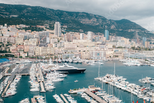 Luxury yachts docked in marina with city skyline and mountains in the background, Port Hercule, Monaco