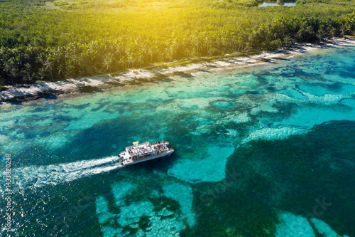 Boats floating along tropical island with palm trees near caribbean sea. Dominican Republic. Aerial view
