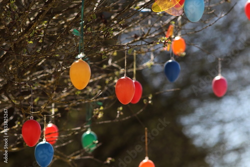 Easter decorations: brightly painted eggs hang from a small bush in the sunlight. Selected Focus.