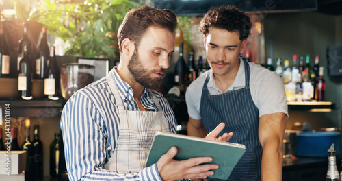 Obraz na płótnie Men, barista and tablet with discussion at cafe with sales report, coach and review schedule at diner. People, mentor and digital touchscreen with app for inventory, menu and training at coffee shop w salonie