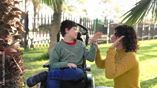Mother playing with son with cerebral palsy in wheelchair in park