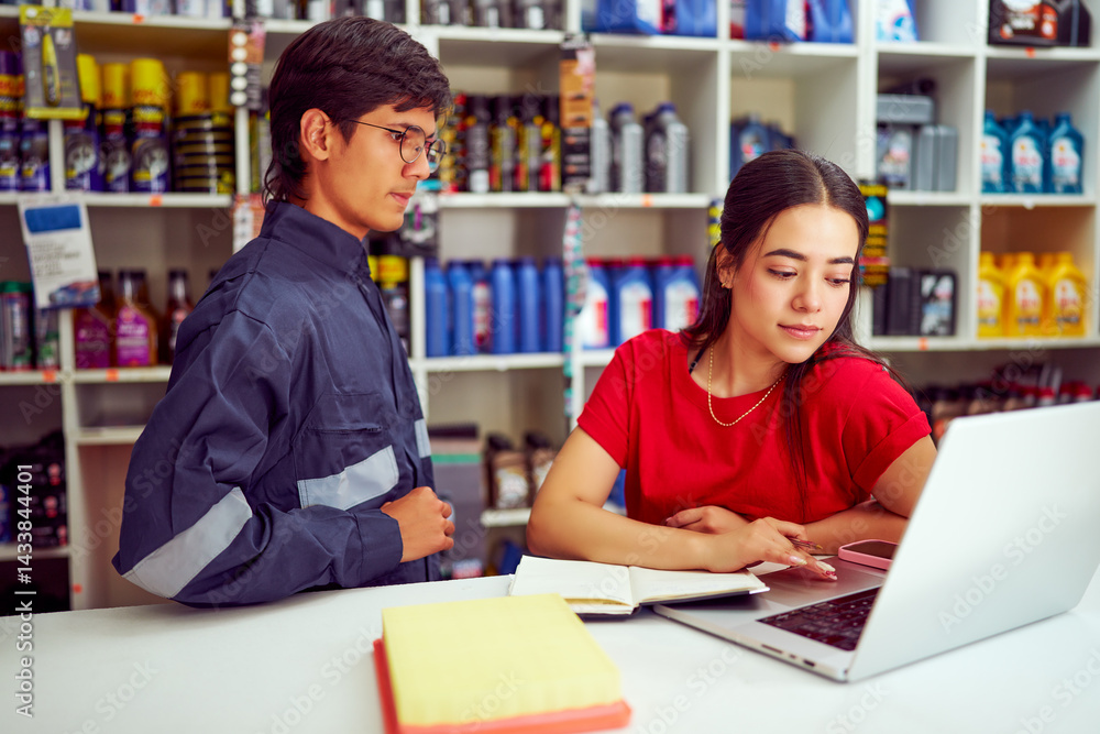 Saleswoman using laptop with mechanic looking in auto parts store Saleswoman using laptop with mechanic looking in auto parts store