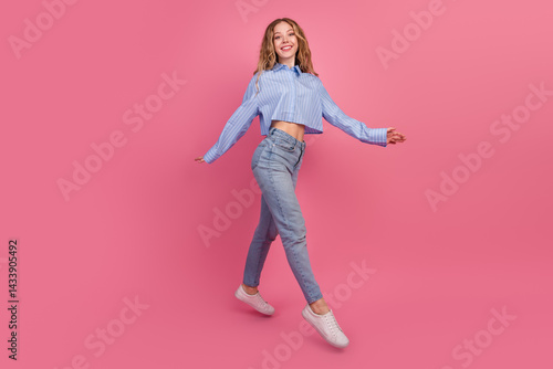 Obraz na płótnie Cheerful young woman in casual outfit enjoying a playful moment against a vibrant pink background, exuding charm and energy w salonie