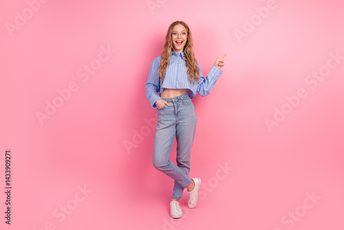 Obraz na płótnie Young woman in casual outfit pointing to the side against pink background, cheerful and stylish with trendy blue striped shirt and jeans w salonie