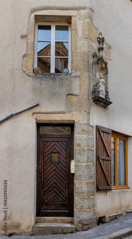 Fototapeta premium Old building facade featuring wooden door, iron balcony, and geometric stone wall pattern.For the background of your photos and collages.