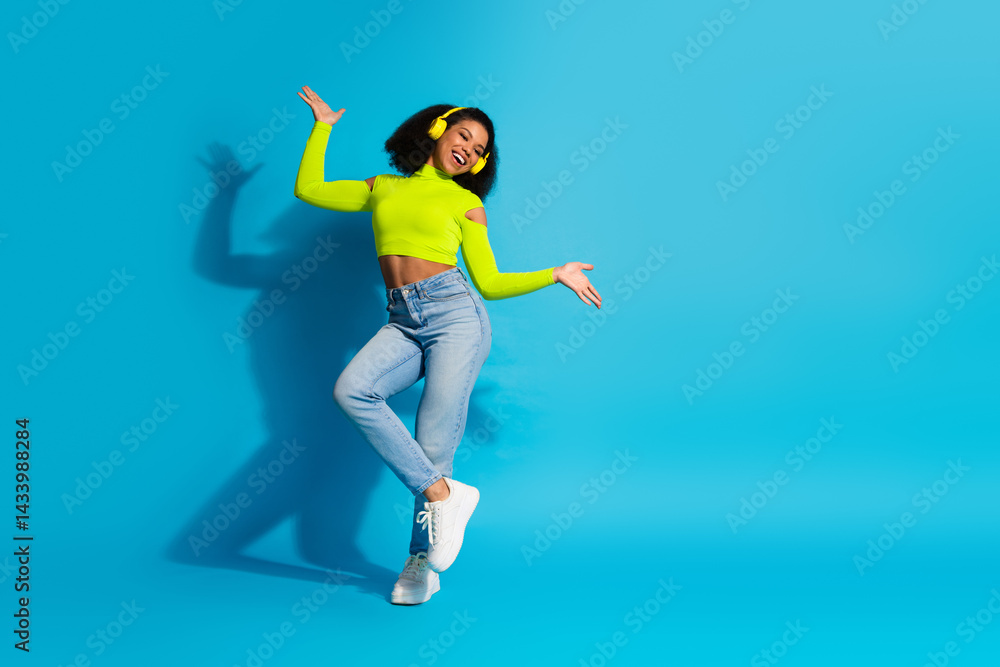 Obraz premium Joyful young woman in vibrant attire radiates positivity against a bold blue background, exuding charm