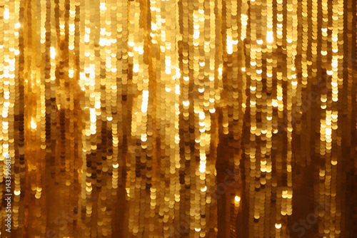 Metallic tinsel background. Bright gold foil fringe curtains hung as interior decor or photo backdrop at a party. Sparkling mylar decoration for festive events. Shiny golden streamers hanging off door
