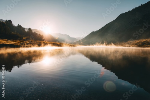 Golden Sunrise Over a Calm Mountain Lake with Mist and Light Flares