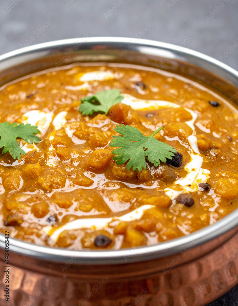 A steaming bowl of flavorful dal makhani, a popular lentil dish from North India, garnished with cream and cilantro, is presented. A steaming bowl of flavorful dal makhani, a popular lentil dish from North India, garnished with cream and cilantro, is presented.