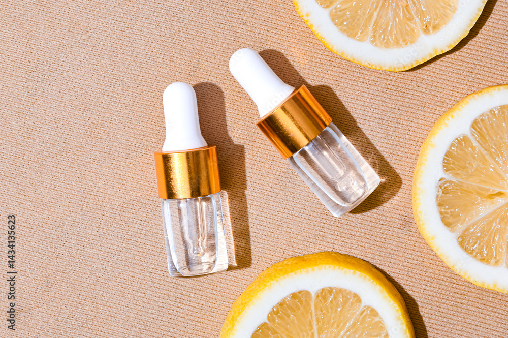 Two transparent serum dropper bottles with golden caps placed on textured beige background, surrounded by fresh lemon slices. Clean, elegant skincare flat lay for beauty and citrus-themed ads