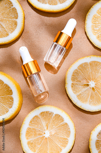 Obraz na płótnie Two transparent serum dropper bottles with golden caps placed on textured beige background, surrounded by fresh lemon slices. Clean, elegant skincare flat lay for beauty and citrus-themed ads w salonie