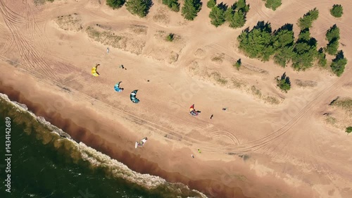 Kite surfers and beachgoers enjoy a sunny day by the water