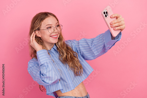 Obraz na płótnie Smiling young woman in a striped blue blouse taking a selfie on a vibrant pink background, expressing joy and confidence w salonie