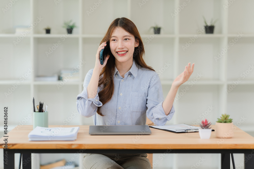 Smiling Asian Woman Talking on Phone at Desk Smiling Asian Woman Talking on Phone at Desk