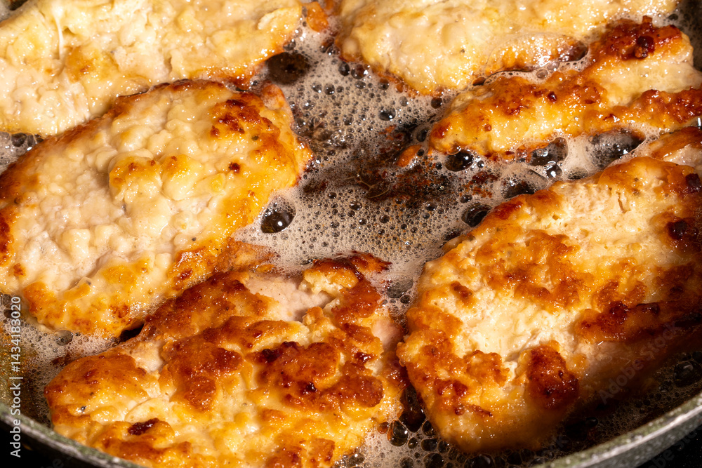 Golden-brown breaded chicken pieces sizzling in hot oil inside a pan.